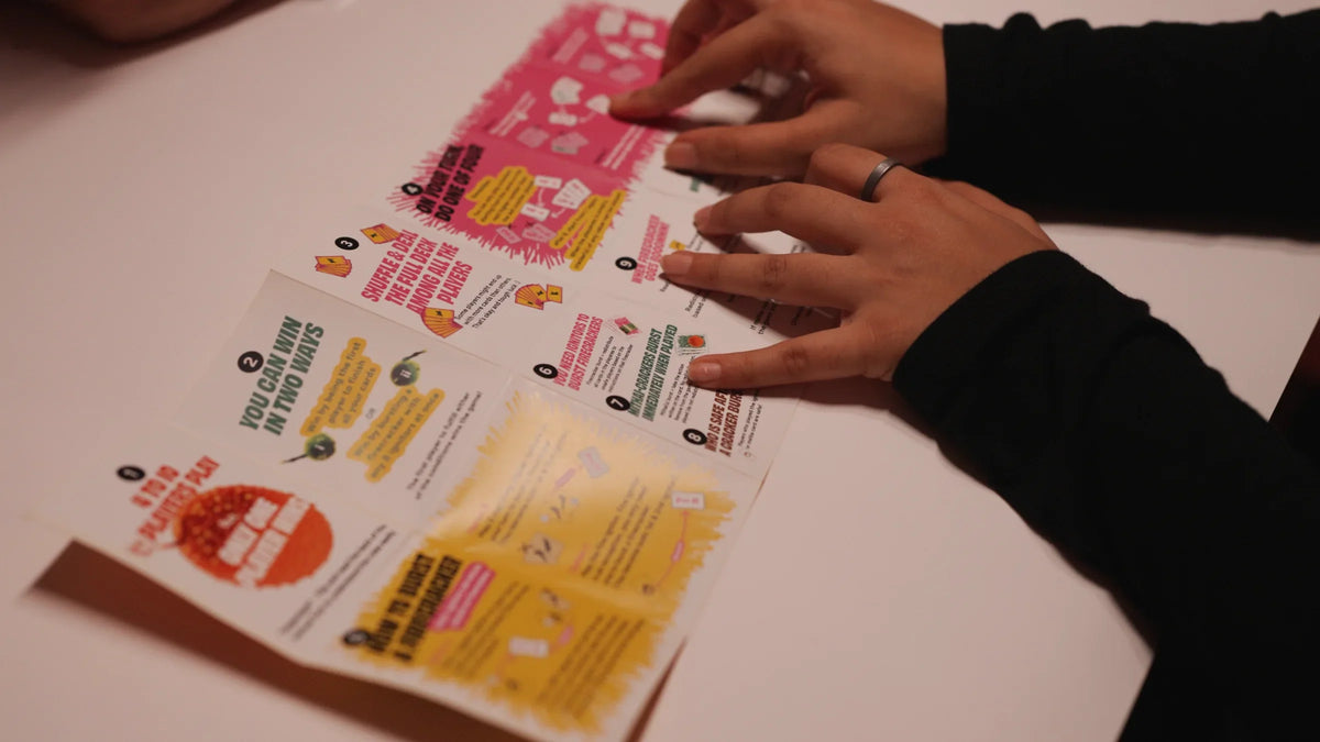 Hands following the illustrated Boom Machale rule manual during a game