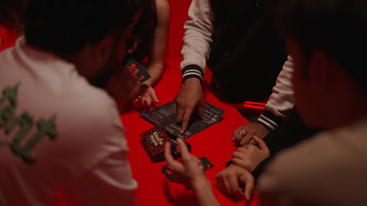 Group learning Khufia Mafia together around the rule sheet on a red table