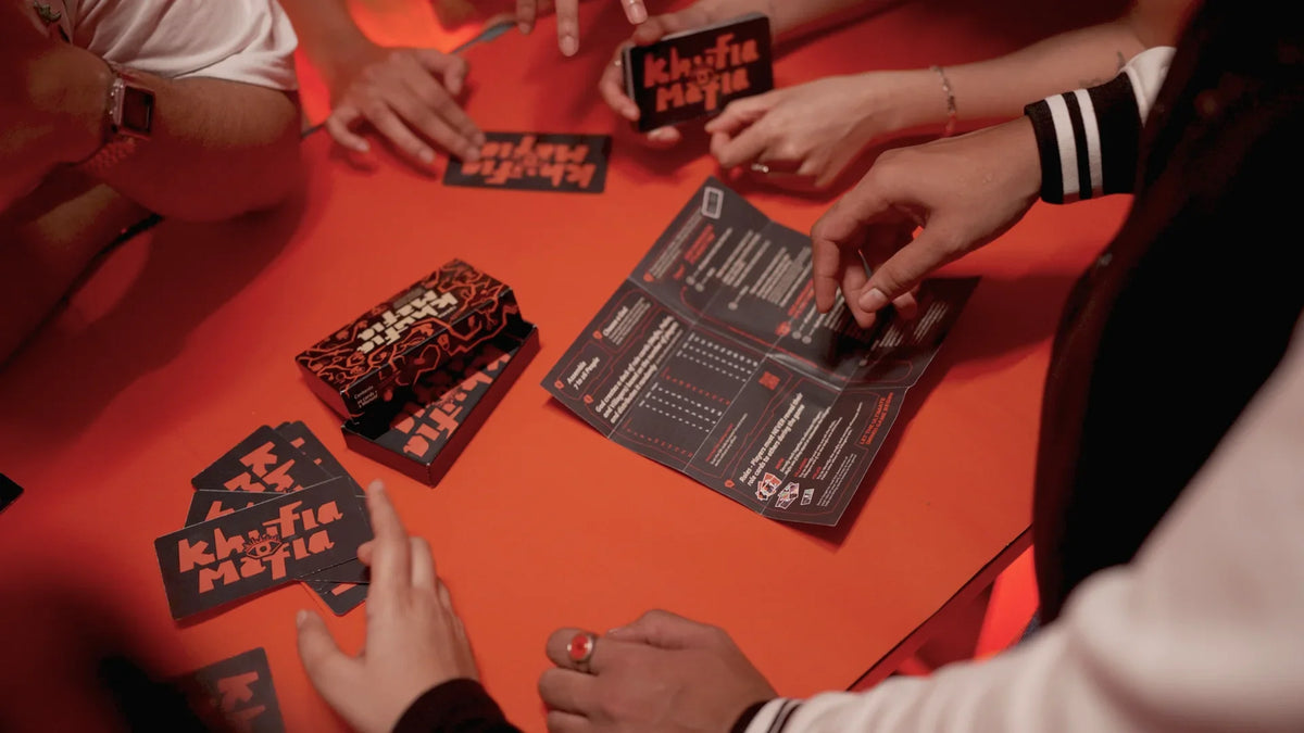 Players gathered around the Khufia Mafia rule sheet and cards on a red table