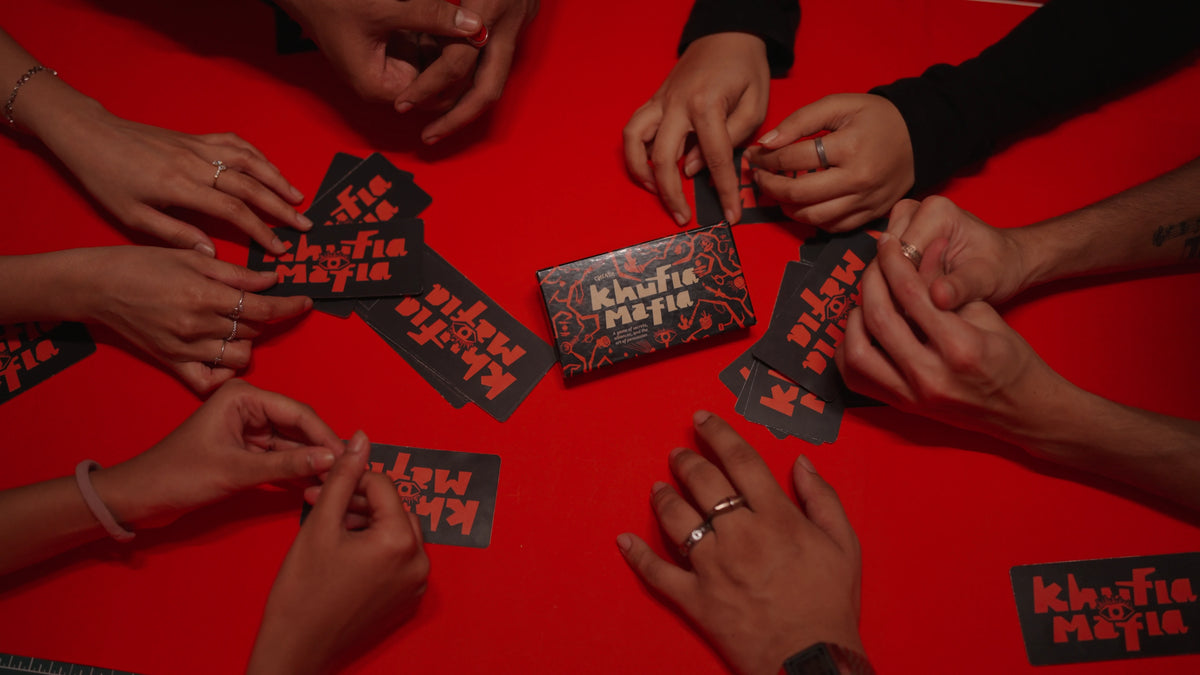 Multiple hands holding Khufia Mafia cards around a table during gameplay