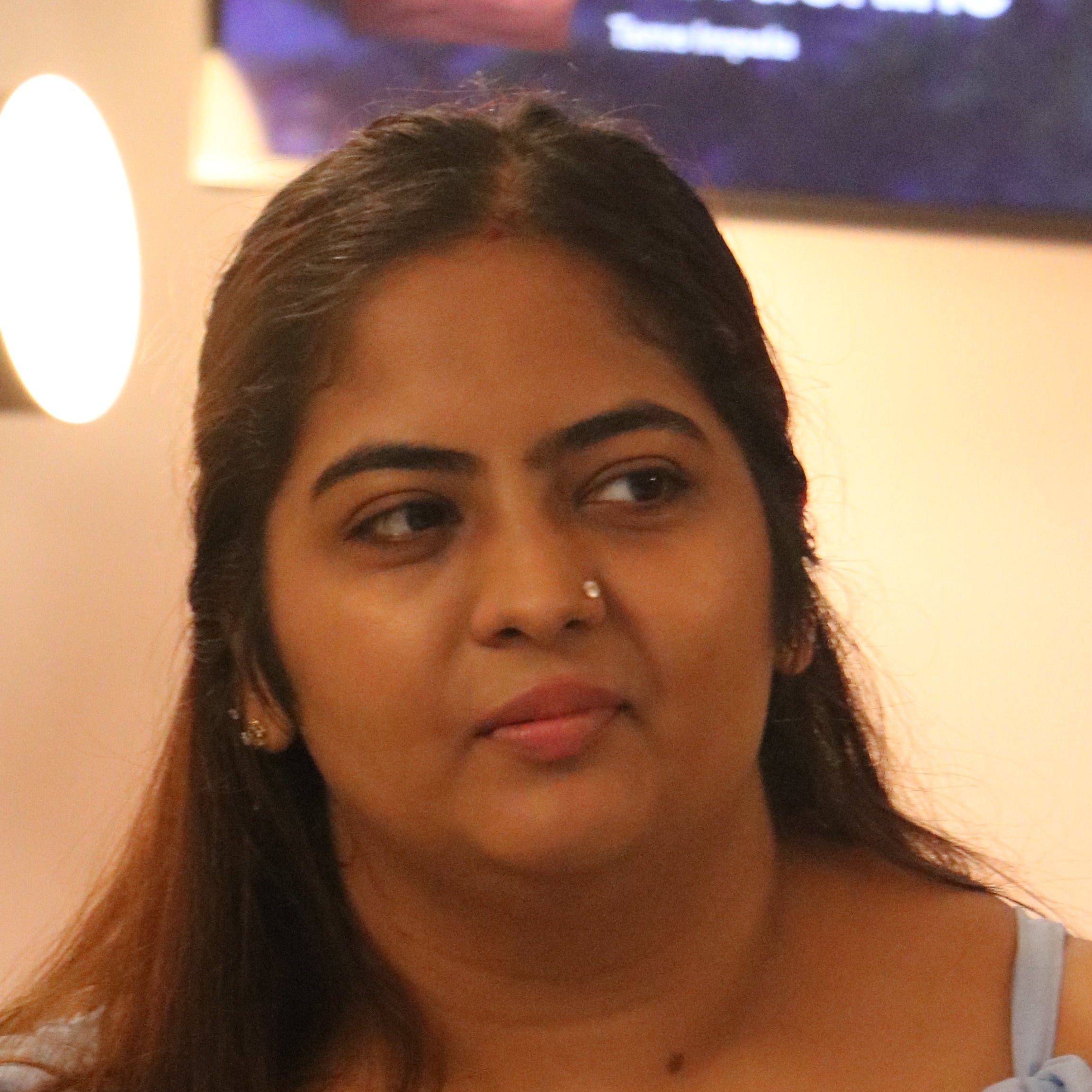Woman in a blue top looking at a screen with a blurred background