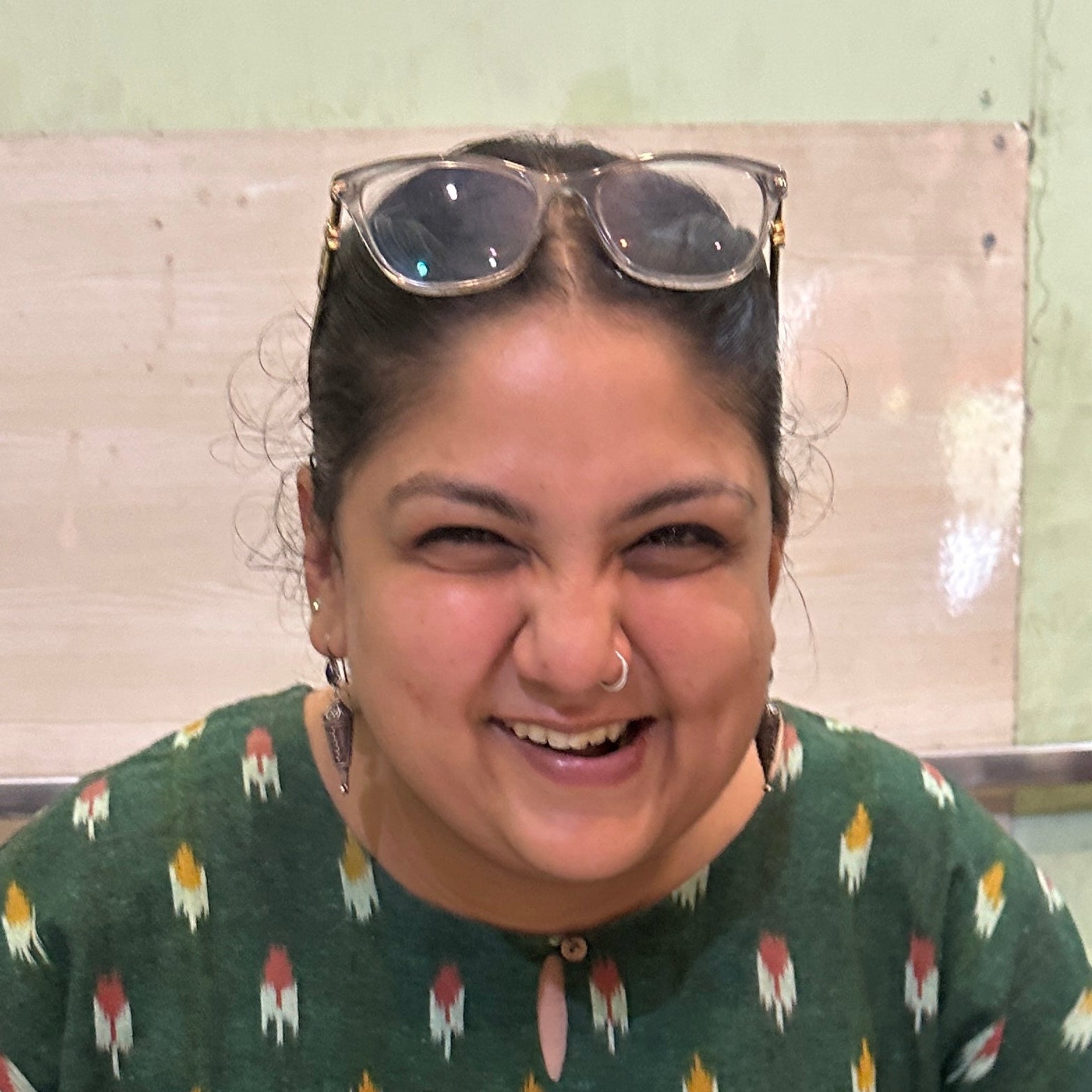 Person sitting at a table with a plate of food and a cup, smiling.